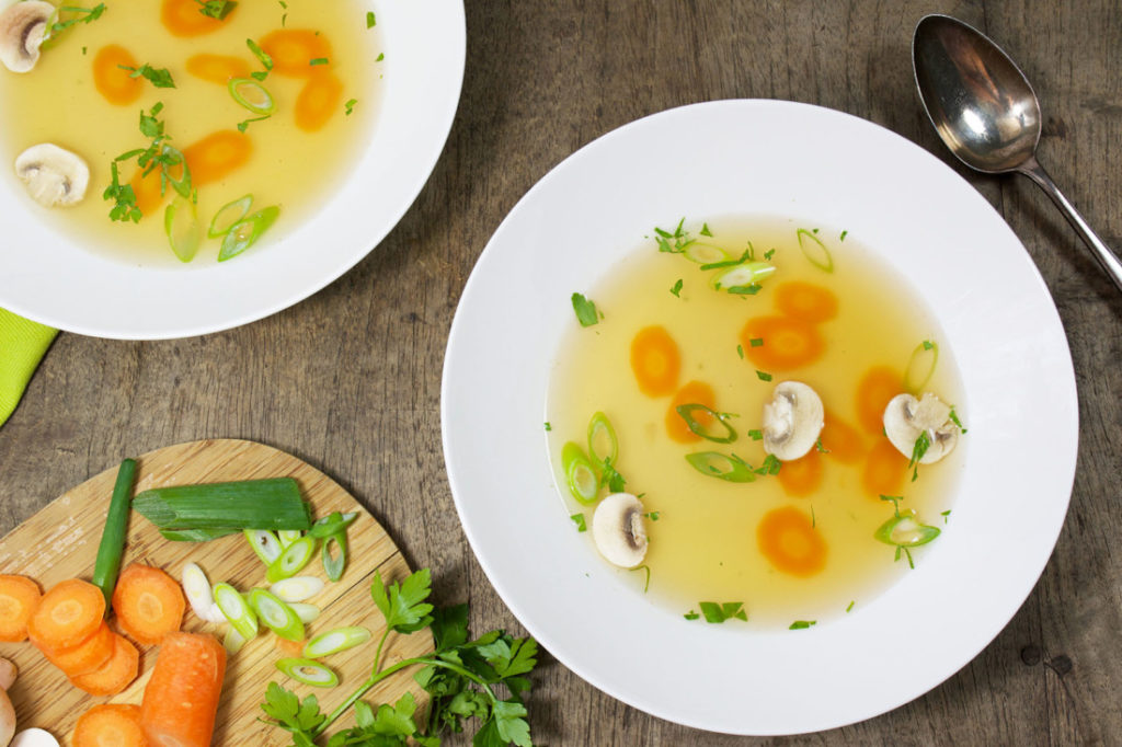 Heldere groentebouillon met wortel en bosui